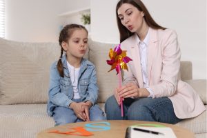 Speech therapist working with little girl indoors